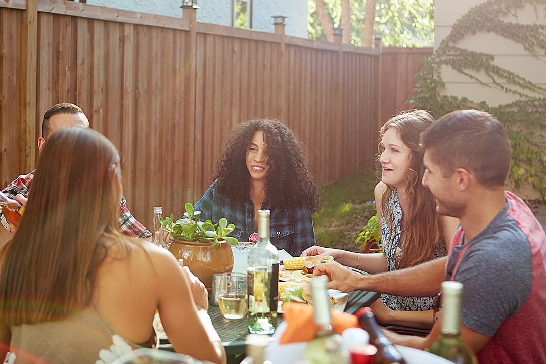 A happy group of friends sharing a meal in a backyard.